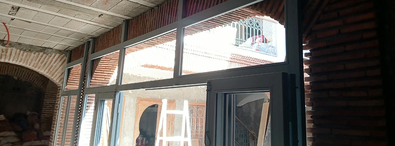 Pose de menuiseries aluminium sous une arcade en brique