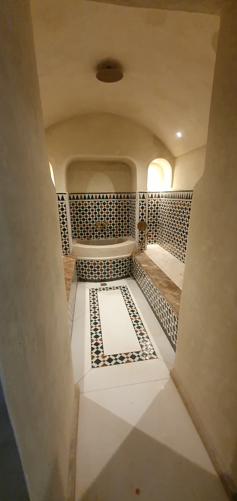Hammam voûté, banquettes et frises en zellige