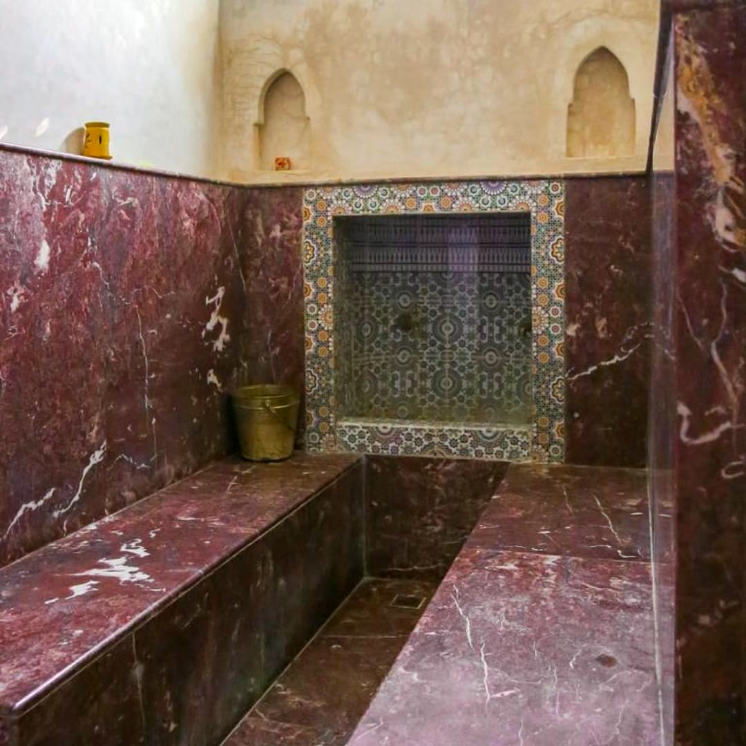 Hammam en marbre rouge, banquettes et niche en zellige