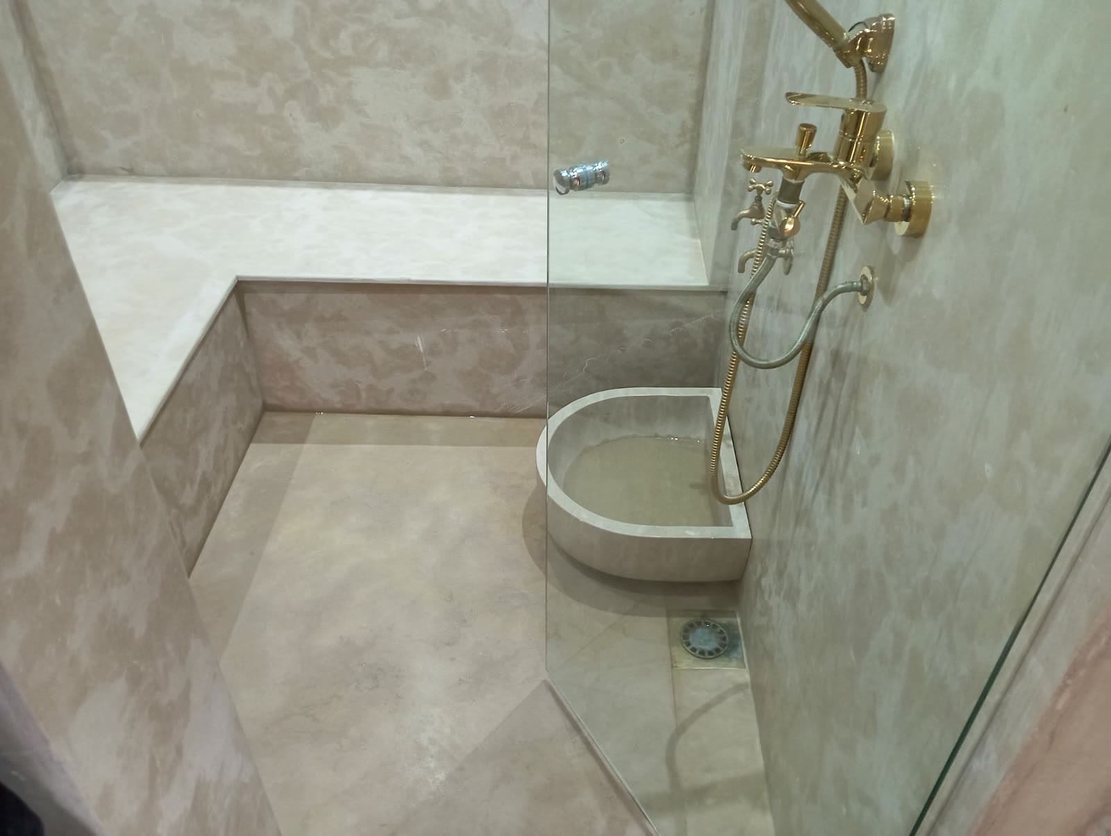 Hammam en pierre beige et robinetterie en laiton